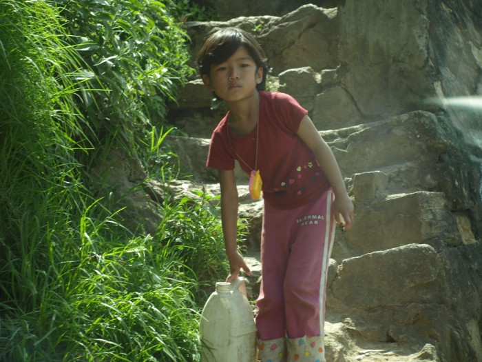 Dziewczynka niosąca wodę do domu z rzeki